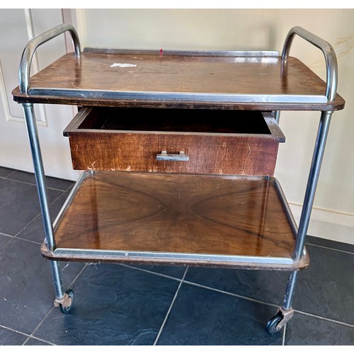 25 - A mid 20thC wood and chrome trolley on wheels with drawer. 70cm h, 63cm l x 41cm d.