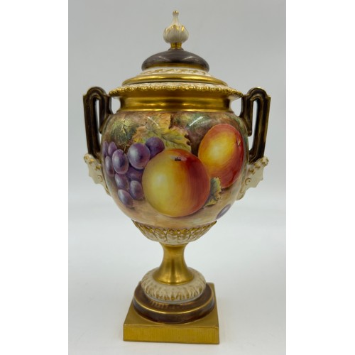 376 - A pair of Royal Worcester twin handled lidded urns with masks to sides on a circular foot with a squ... 