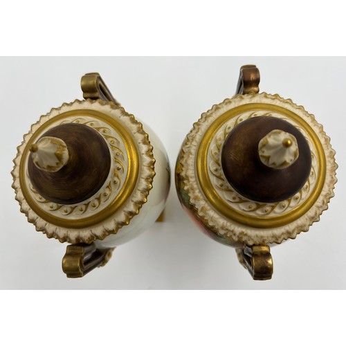 376 - A pair of Royal Worcester twin handled lidded urns with masks to sides on a circular foot with a squ... 