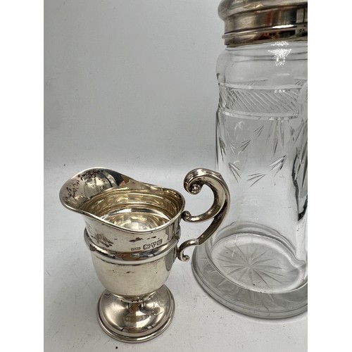 777 - A silver topped glass sugar sifter Chester 1911, maker J &R Griffin together with a silver cream jug... 