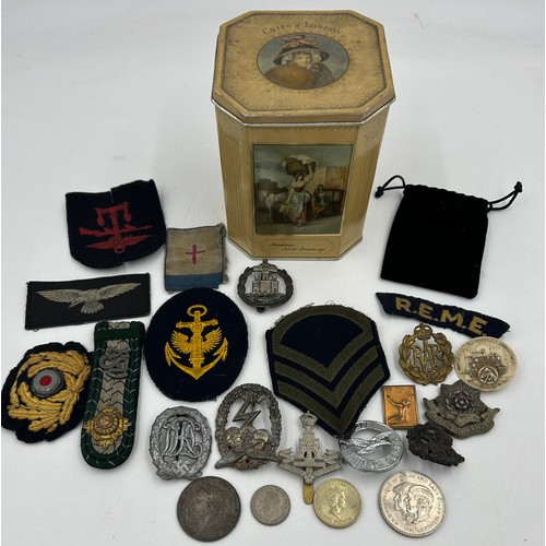 1004 - A selection of military badges in a Huntley and Palmers biscuit tin to include R.A.F beret badges, D... 