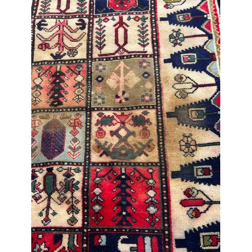 1103 - A red ground wool rug with panel designs. Approx. 167 x 280cm. (not including tassels).