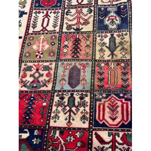 1103 - A red ground wool rug with panel designs. Approx. 167 x 280cm. (not including tassels).