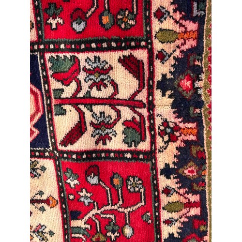 1103 - A red ground wool rug with panel designs. Approx. 167 x 280cm. (not including tassels).