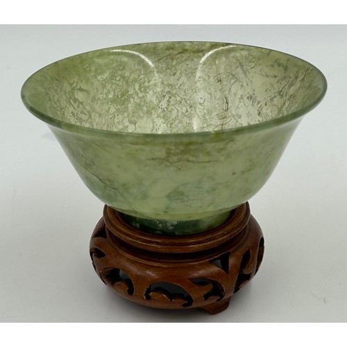 1210 - A Chinese small jade bowl on a wooden stand, 9.8cm diameter, height 4.8cm (excluding stand) together... 