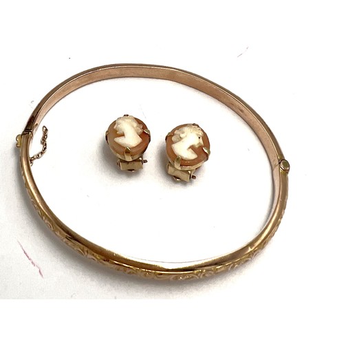 574 - A 9 carat gold hinged bangle, weight 5.8 gm together with a pair of shell cameo clip on earrings mou... 