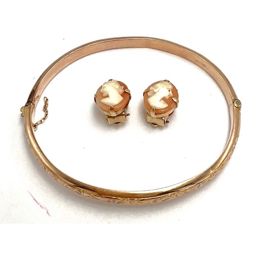 574 - A 9 carat gold hinged bangle, weight 5.8 gm together with a pair of shell cameo clip on earrings mou... 