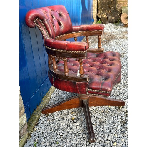 39 - A red leather upholstered swivel Captain's office chair, with padded back and arm rest on 4 supporti... 