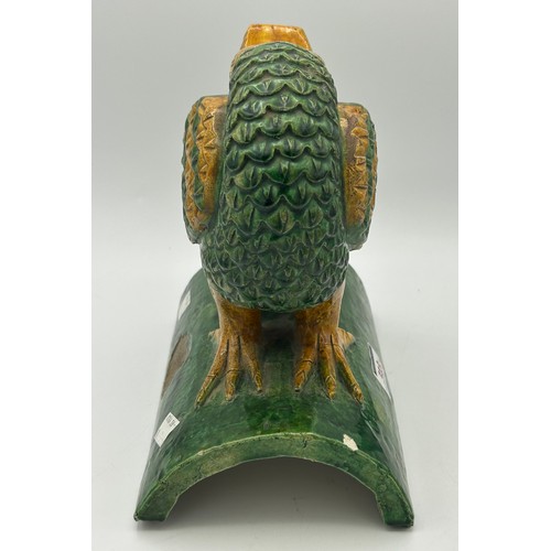 246 - A Chinese tile-work model of a bird, with its head bent round between its wings and decorated with y... 