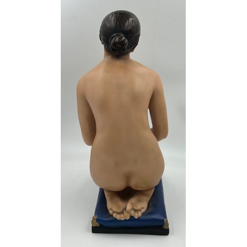 321 - A figure of a pensive female nude, kneeling on a blue cushion. Approx. 47cm h. Base 29 x 16.5cm.