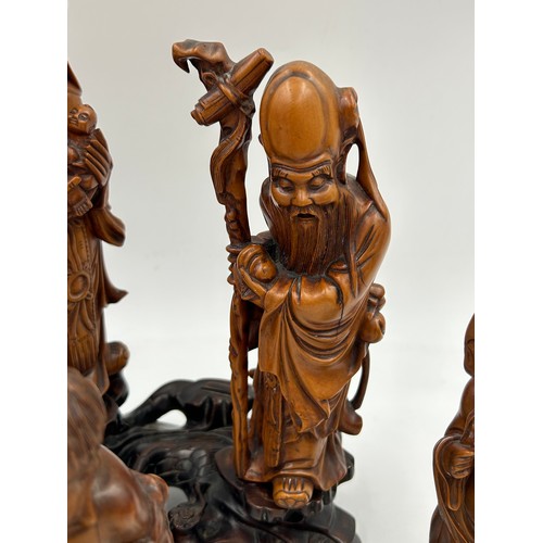 944 - A collection of oriental figures to include 5 x wooden carved figures on stands tallest 28cm and 3 x... 