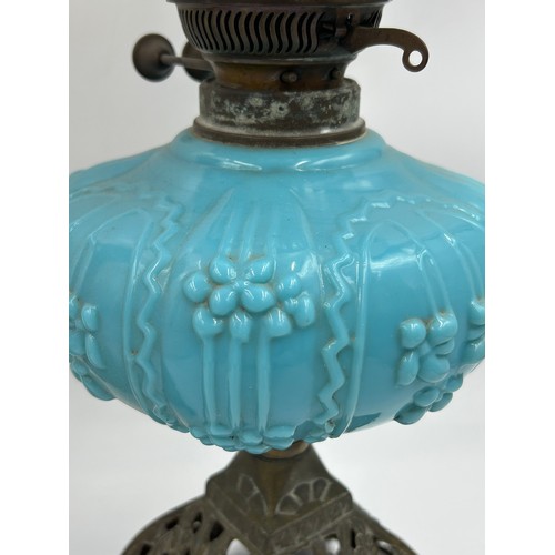 976 - Two oil lamps, one complete with a blue moulded glass reservoir and the other a brass column depicti... 