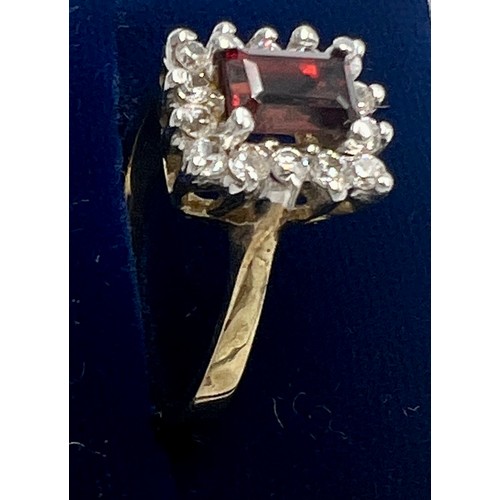 675 - A 9 carat gold ring set with red gemstone surrounded by clear stones. Size N, weight 3gm.