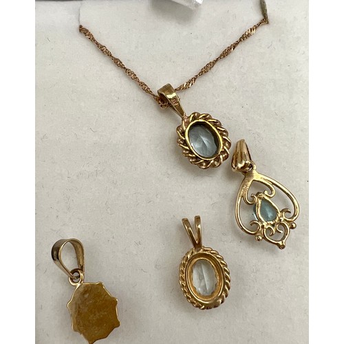 694 - Four 9 carat gold pendants, three set with pale blue stones, one with 9 carat gold chain and a ladyb... 