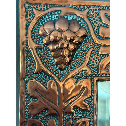 1027 - An Arts and Crafts copper wall mirror with grape design. 40 x 36cm.