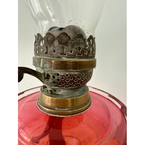 979 - A 19thC cranberry and brass oil lamp with black ceramic base. 48cm h to fitting.