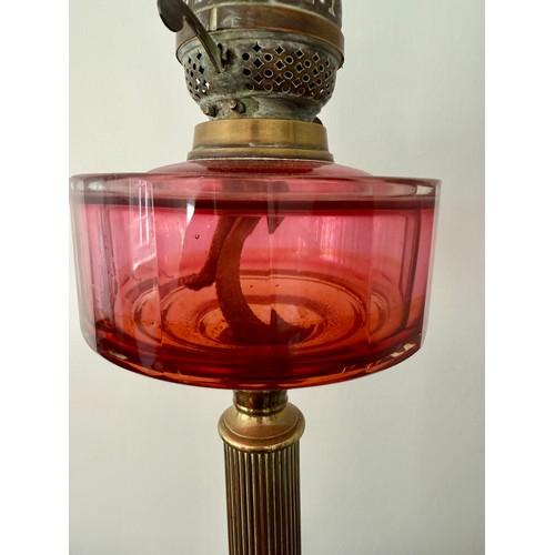 979 - A 19thC cranberry and brass oil lamp with black ceramic base. 48cm h to fitting.