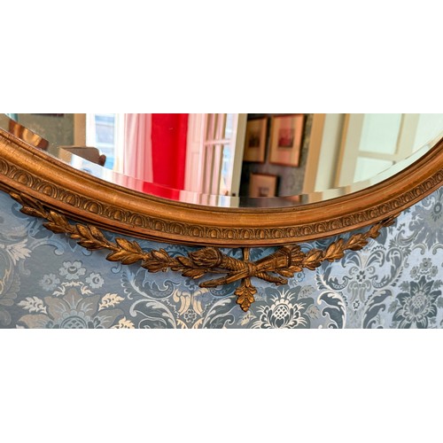 1030 - A bevel edged oval gilt framed wall mirror. 82 h x 84cm w.