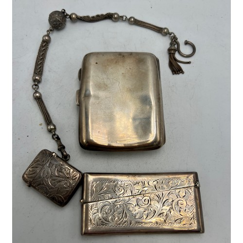 853 - Silver card case with foliate scroll engraving, vesta case on decorative chain and a cigarette case.... 