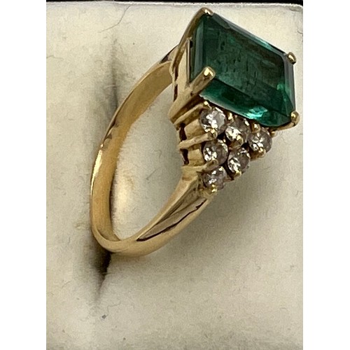 701 - An 18 carat yellow gold ring set with trap cut emerald with six stone diamond set shoulders. Emerald... 