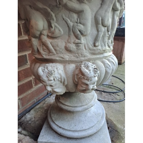 7 - A pair of reconstituted stone garden urns with putti decoration. 65 h x 54cm d.