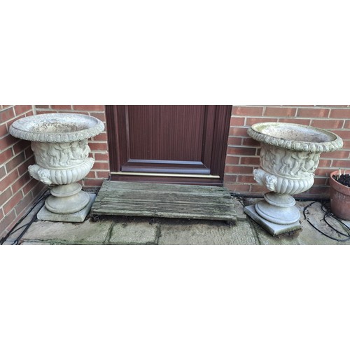 7 - A pair of reconstituted stone garden urns with putti decoration. 65 h x 54cm d.