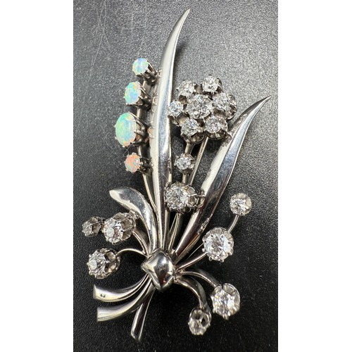 A platinum brooch in the form of a flower set with four opals and sixteen diamonds. 6cm x 3cm. Weight 15.3gm. 2-2.5 carats diamonds, 2.20 traditional cut diamonds, S1 clarity, G/H colour.