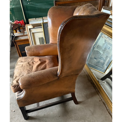 10 - A brown leather wing backed armchair. 80cm w x 106cm h to back.