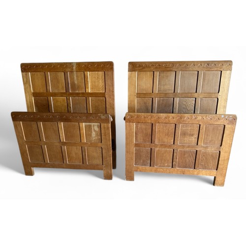 A pair of Robert 'Mouseman' Thompson, oak panelled single (3 feet wide) beds each with signature mouse. These are complete with Vono side irons and metal and wooden bases.