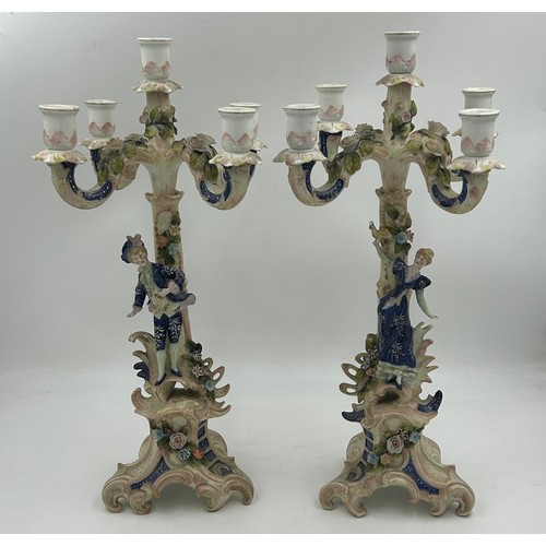 418 - A pair of ornate porcelain figural four branch candelabras in the Dresden style. 47cm h.