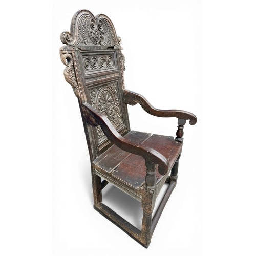 43 - A 17thC carved oak wainscot armchair with high back rest, down swept arm rests, carving to the top a... 