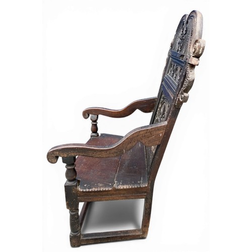 43 - A 17thC carved oak wainscot armchair with high back rest, down swept arm rests, carving to the top a... 
