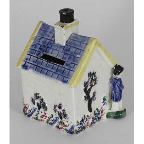 39 - An early 19th century Staffordshire pottery money box shaped as a cottage, flanked by male and femal... 