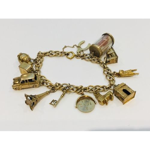 196 - A 9ct gold charm bracelet with twelve 9ct gold charms, including a Hackney cab and an Eiffel Tower c... 