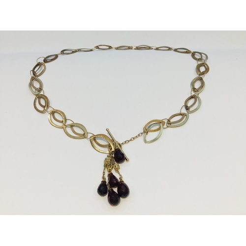 198 - A 9ct gold interlinking design necklace with 5 x briolette cut garnets on a bar link fastening, weig... 