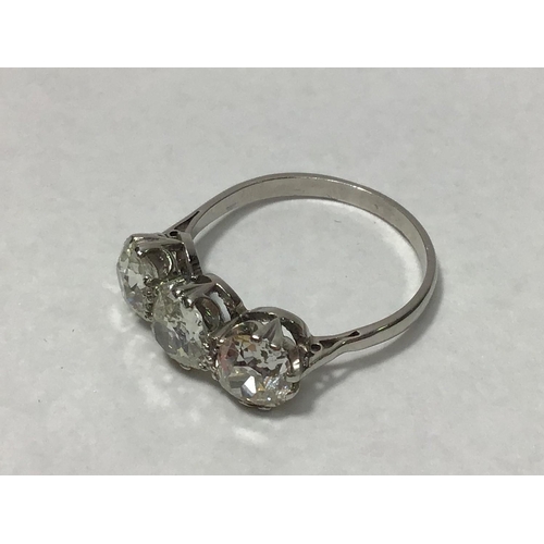 204 - A platinum three-stone diamond ring, claw set with old-cut diamonds, the diamonds weighing a total o... 