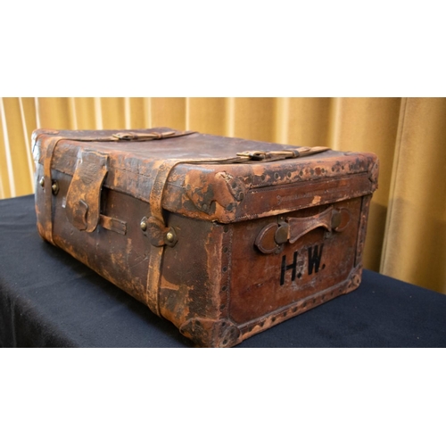 129A - A brown leather suitcase by Finnigans of Manchester, with leather straps, brass lock and with handle... 