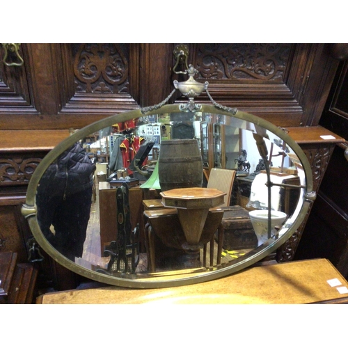 289C - A 20th century oval Adam style bevelled wall mirror, brass frame surmounted with urn finial and swag... 