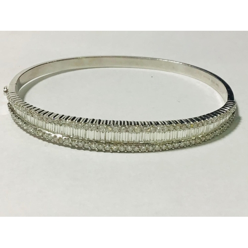 222 - A ladies 18ct white gold triple diamond set bangle. To the centre is set a graduated row of tapered ... 