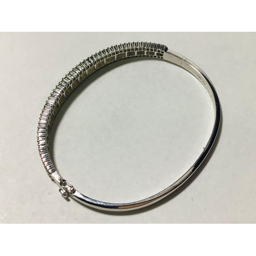 222 - A ladies 18ct white gold triple diamond set bangle. To the centre is set a graduated row of tapered ... 