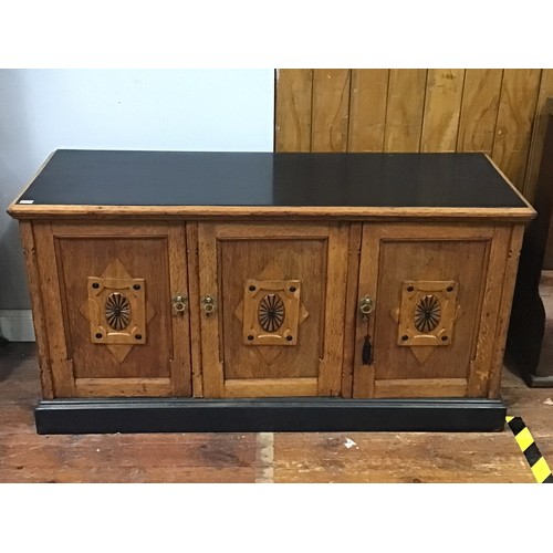 420 - An oak sideboard with black painted top, sides and plinth base, three cupboard doors each with raise... 