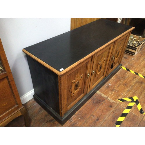 420 - An oak sideboard with black painted top, sides and plinth base, three cupboard doors each with raise... 