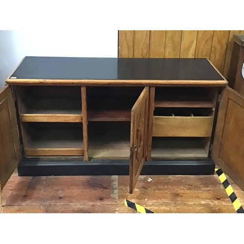 420 - An oak sideboard with black painted top, sides and plinth base, three cupboard doors each with raise... 