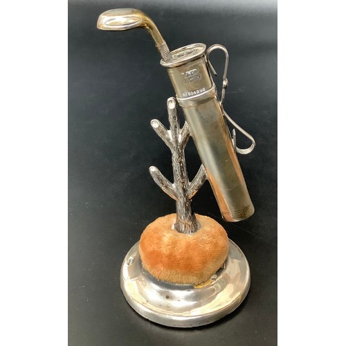 43 - A novelty silver pin cushion modelled as a golf bag leaning on a tree, with circular cushion raised ... 