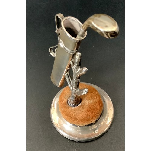 43 - A novelty silver pin cushion modelled as a golf bag leaning on a tree, with circular cushion raised ... 