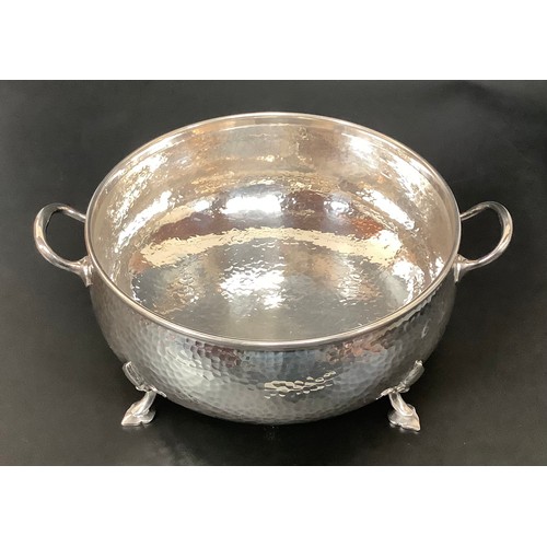 42 - A silver-plated Arts and Crafts, twin-handled, planished bowl by Mappin and Webb, raised on four sha... 