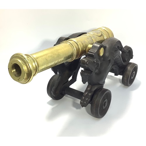 450 - A brass table signalling cannon raised on cast iron carriage modelled as stylised dragons, to four w... 