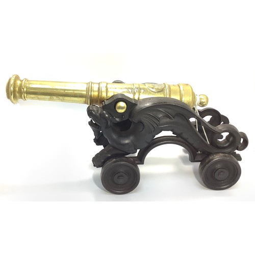 450 - A brass table signalling cannon raised on cast iron carriage modelled as stylised dragons, to four w... 