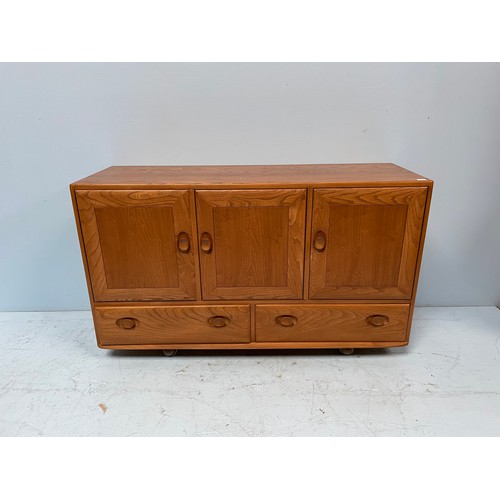 612 - An Ercol Blonde elm Windsor sideboard, with three cupboard doors enclosing shelves, above two drawer... 