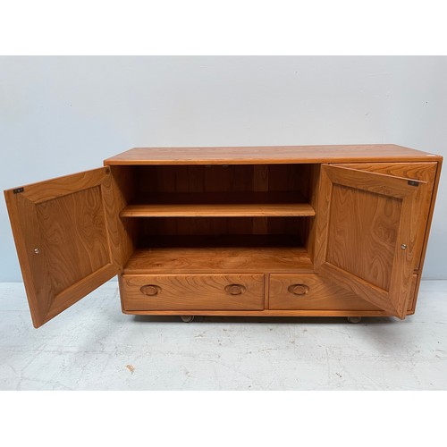 612 - An Ercol Blonde elm Windsor sideboard, with three cupboard doors enclosing shelves, above two drawer... 